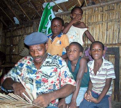 A Rabelados elder weaving inside a home while four children watch